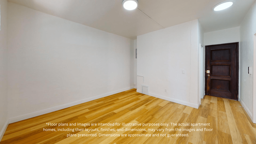 a living room with white walls and wood flooring and a wooden door