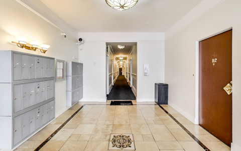 A hallway with a brown door and a black trash bin.