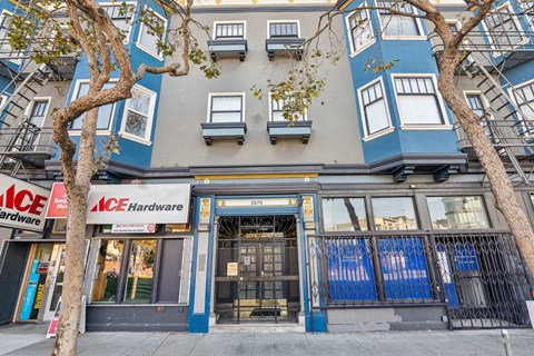 A building with a blue and white facade has a sign that reads "ACE Hardware.".