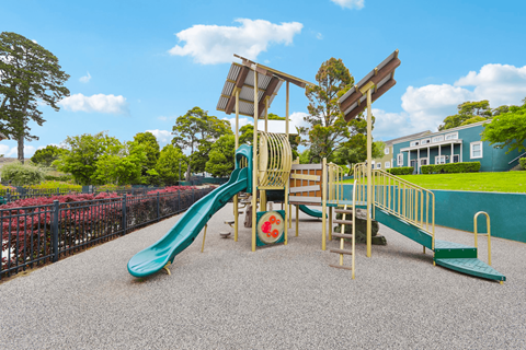 Playground located in an apartment community, featuring a slide equipped with a protective cover for added safety.