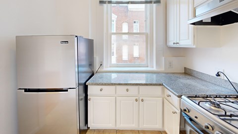 A kitchen with a stainless steel refrigerator and a stove top oven.