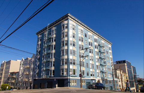 A large blue building with a lot of windows and a few cars parked in front.