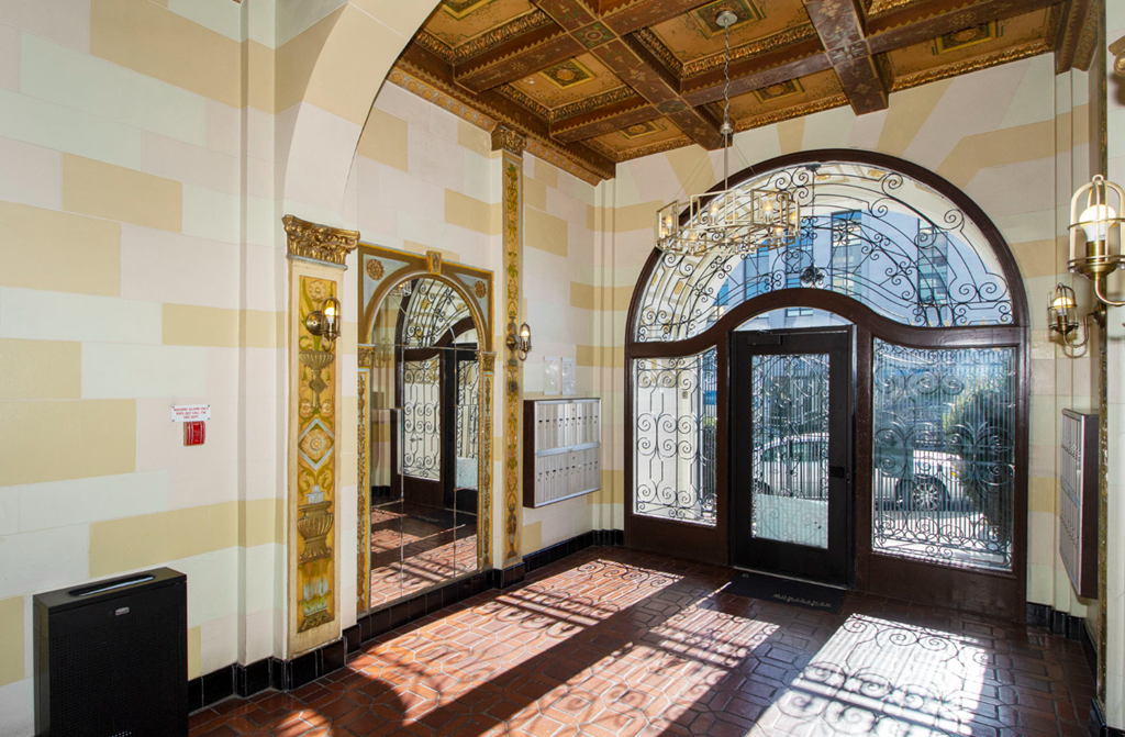 Lobby entrance to a building featuring a large arched door and a large mirror
