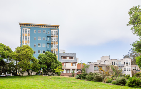 A blue building with a yellow trim is in the background of a grassy area.