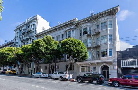 A row of old buildings with cars parked in front.