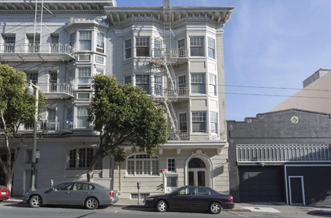 Two cars are parked in front of a large building.