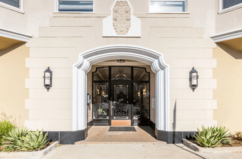 A beige building with a black door and a white archway above it.
