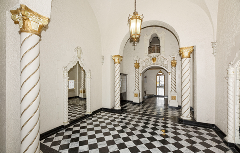 the lobby of the building has a checkered floor and white and gold columns