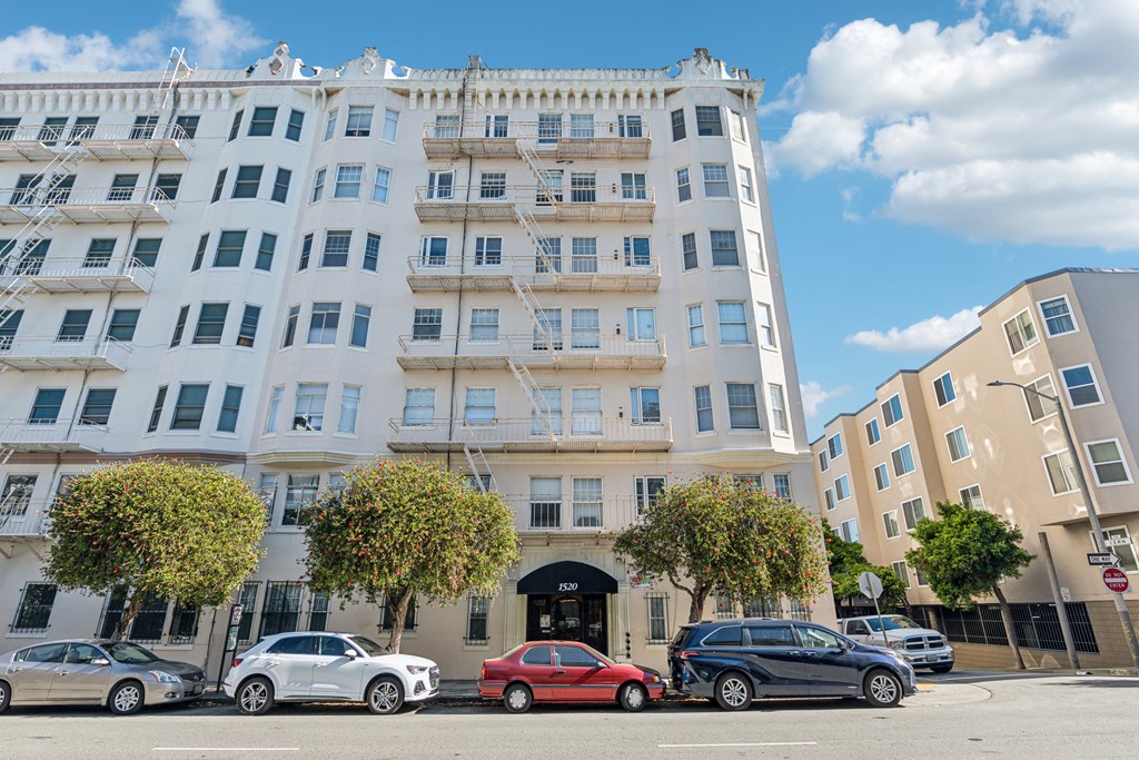 A red car is parked in front of a white building.
