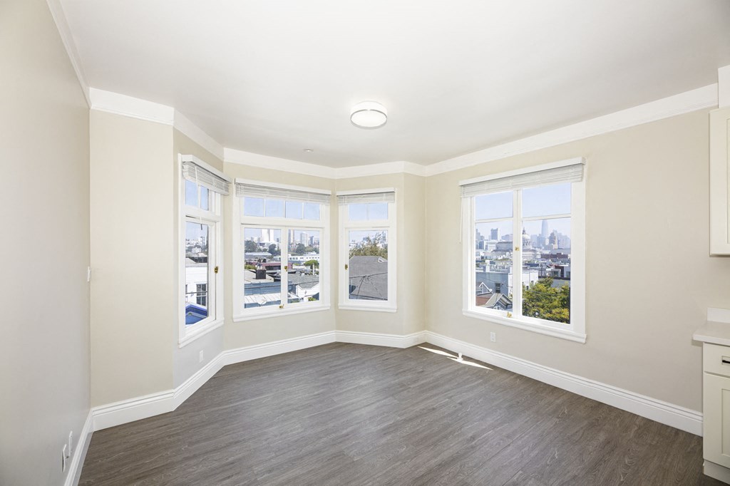 an empty living room with four windows and a wood floor