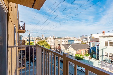 A balcony overlooks a street with cars and buildings.