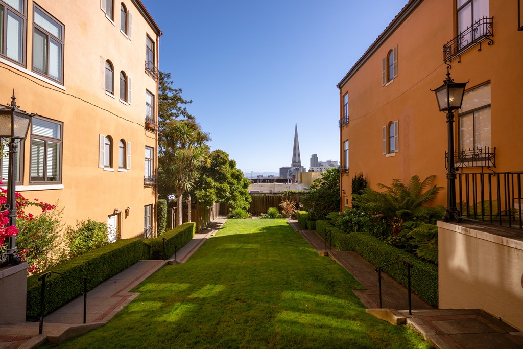 A green lawn leads to a tall building in the distance.
