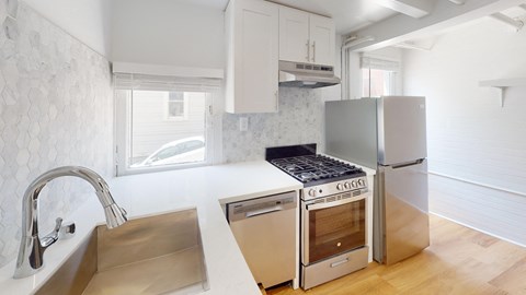 a white kitchen with stainless steel appliances and a sink