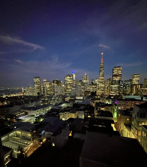 A cityscape at night with a tall building lit up in blue and orange.