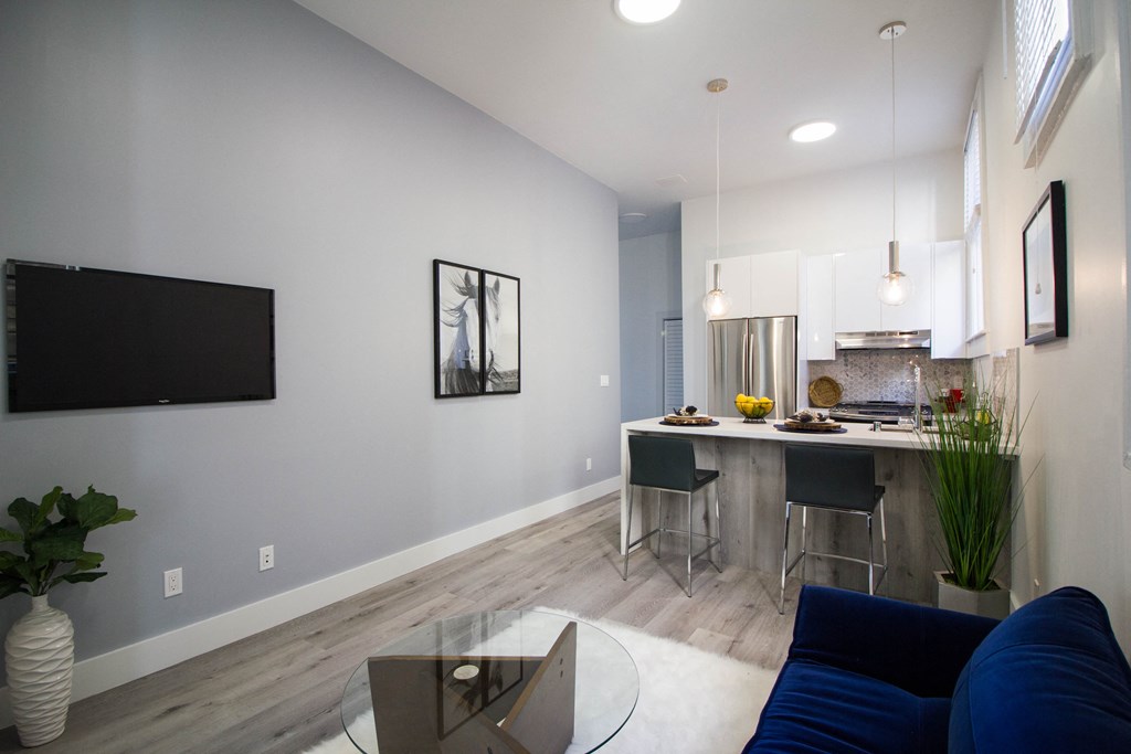 Open-concept living room and kitchen area with upgraded appliances and a stylish dining table bar.