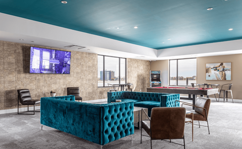 a clubhouse with blue couches and chairs and a pool table