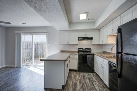 A kitchen with black appliances and white cabinets.
