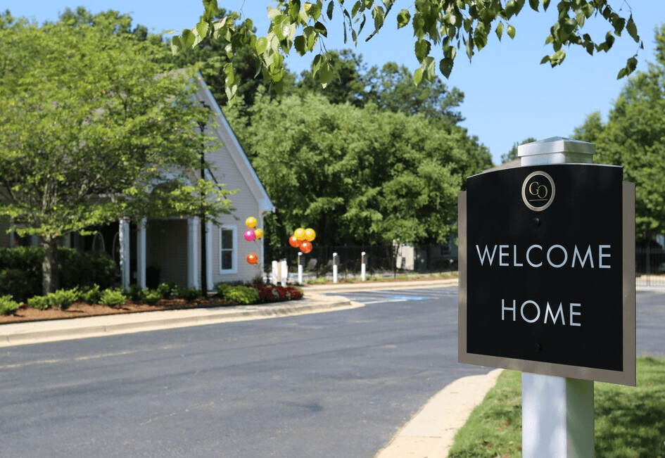A sign that says "Welcome Home" stands in front of a house.