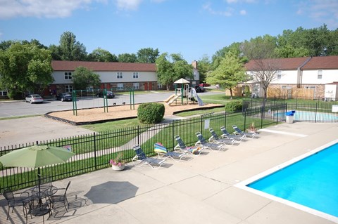 Swimming pool with lounge chairs and playground at Country Lake Estates Apartments, Indianapolis, IN 46229