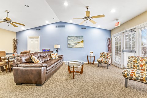 A living room with a brown couch and a ceiling fan.