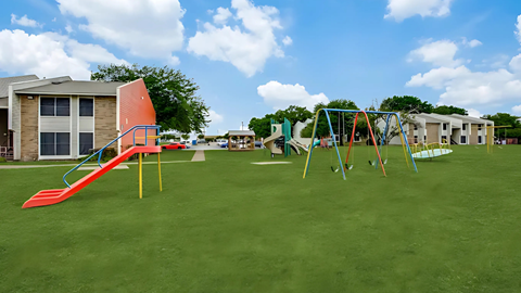 A playground with a red slide and a green lawn.