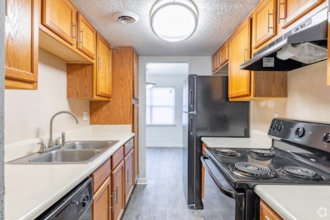 A kitchen with wooden cabinets and a black refrigerator.