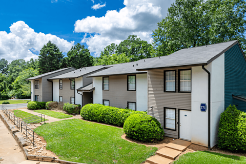 a white and gray apartment building with green grass and trees at Glen Hollow, Decatur, GA