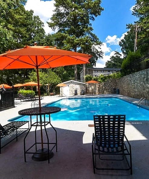 a swimming pool with a table with an umbrella and two chairs at Tucker Square, Stone Mountain 30083