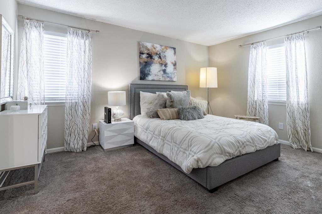 a bedroom with a bed and windows with white curtains at Tucker Square, Georgia