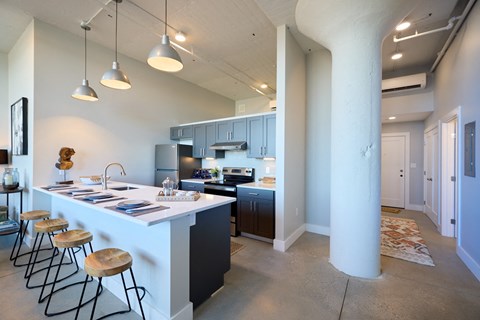 A kitchen with a white counter top and bar stools.