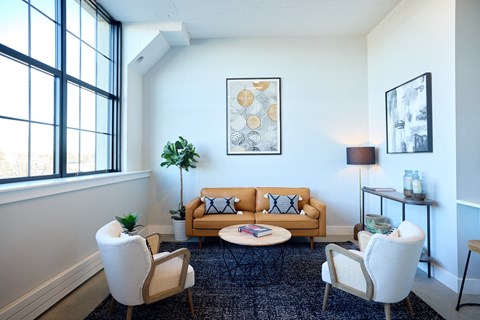 A living room with a yellow couch and a blue rug.