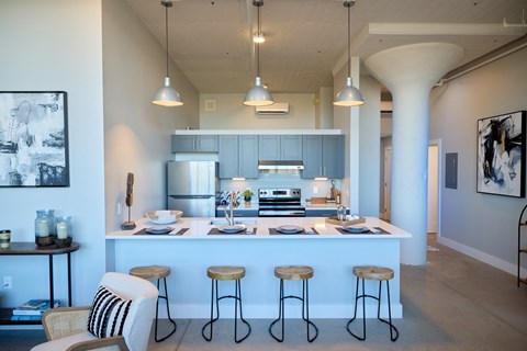 A kitchen with a white island and bar stools.