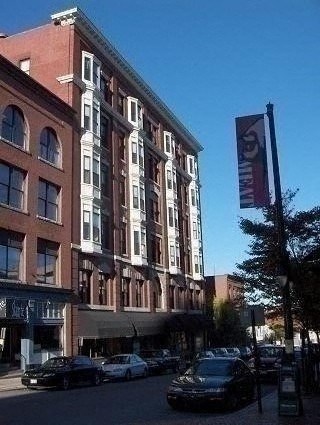 A tall building with a red brick facade stands on a street corner.