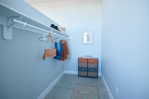 A hallway with a bench and a bag hanging on a hook.