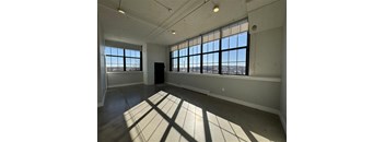 A large empty room with a view of the city through the windows.