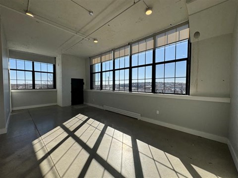 A large empty room with a view of the city through the windows.