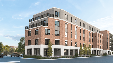 A large red brick building with a white trim around the windows and a parking lot in front.