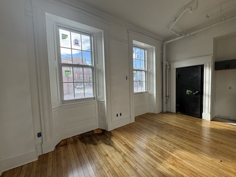 A room with wooden floors and two windows.