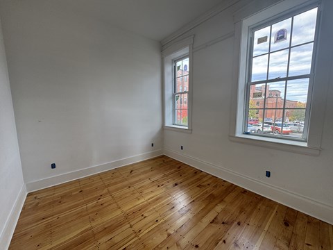 A room with wooden floors and two windows.