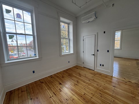 A room with wooden floors and two windows.