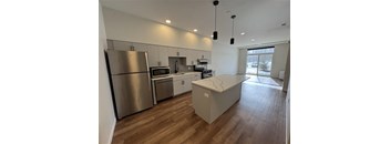 A modern kitchen with stainless steel appliances and wooden flooring.