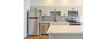 A kitchen with a stainless steel refrigerator and a white countertop.