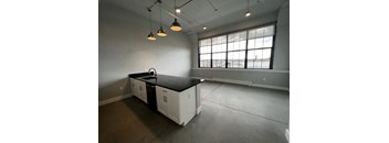 A kitchen with white cabinets and black countertops is empty and ready for renovation.