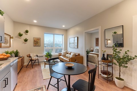 A well-lit, modern kitchen and living room with a dining table and chairs.