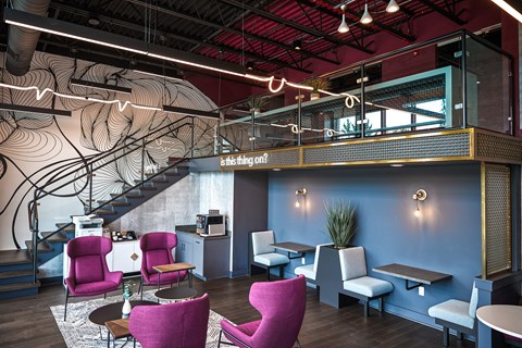 A modern cafe with a spiral staircase and pink chairs.