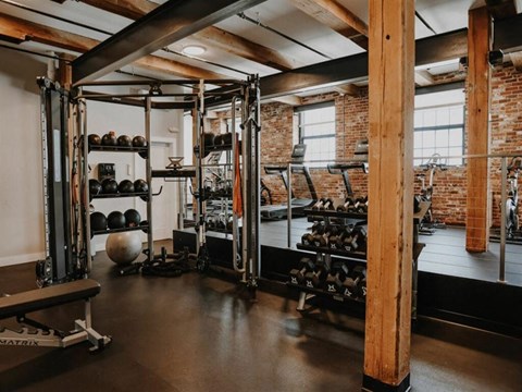 a gym with weights and a brick wall and a window