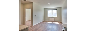 A spacious room with wood flooring and a window.