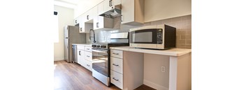 A kitchen with a black microwave on a white counter.