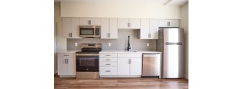 A modern kitchen with a stainless steel refrigerator, oven, and microwave.