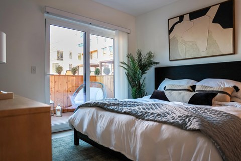 a bedroom with a bed and a sliding glass door to a balcony